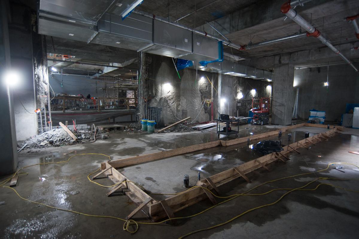 Construction site with concrete forms and steel framework for elevator shafts on transit station platform.