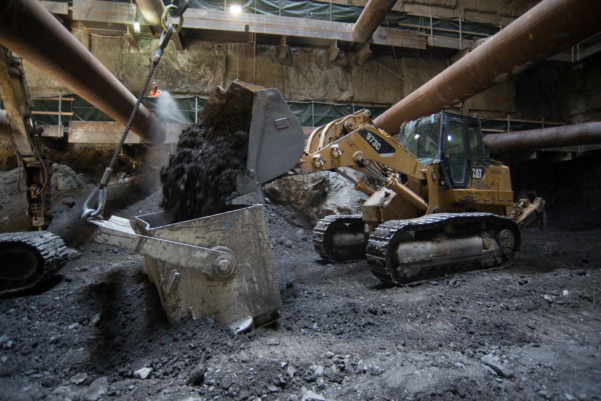 Excavation equipment loading debris into a bin at Chinatown Station construction site underground.