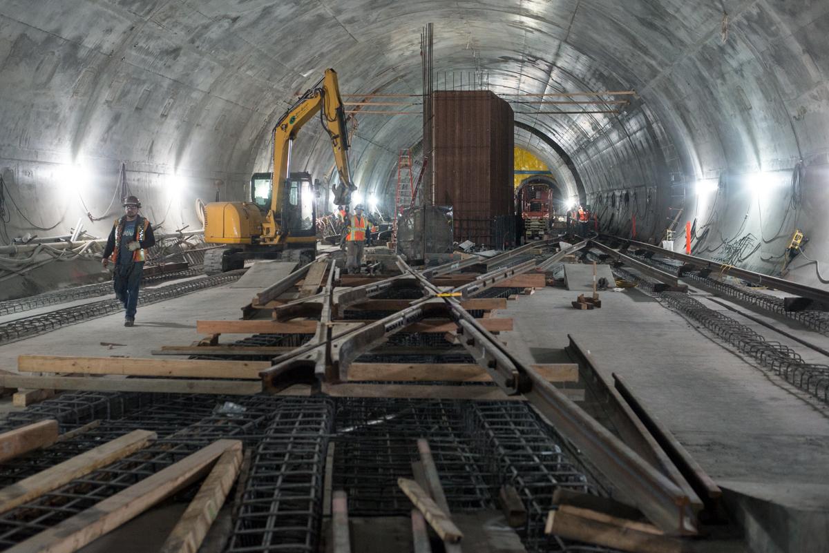 Construction workers and equipment inside an underground tunnel installing railway tracks for the Central Subway project.