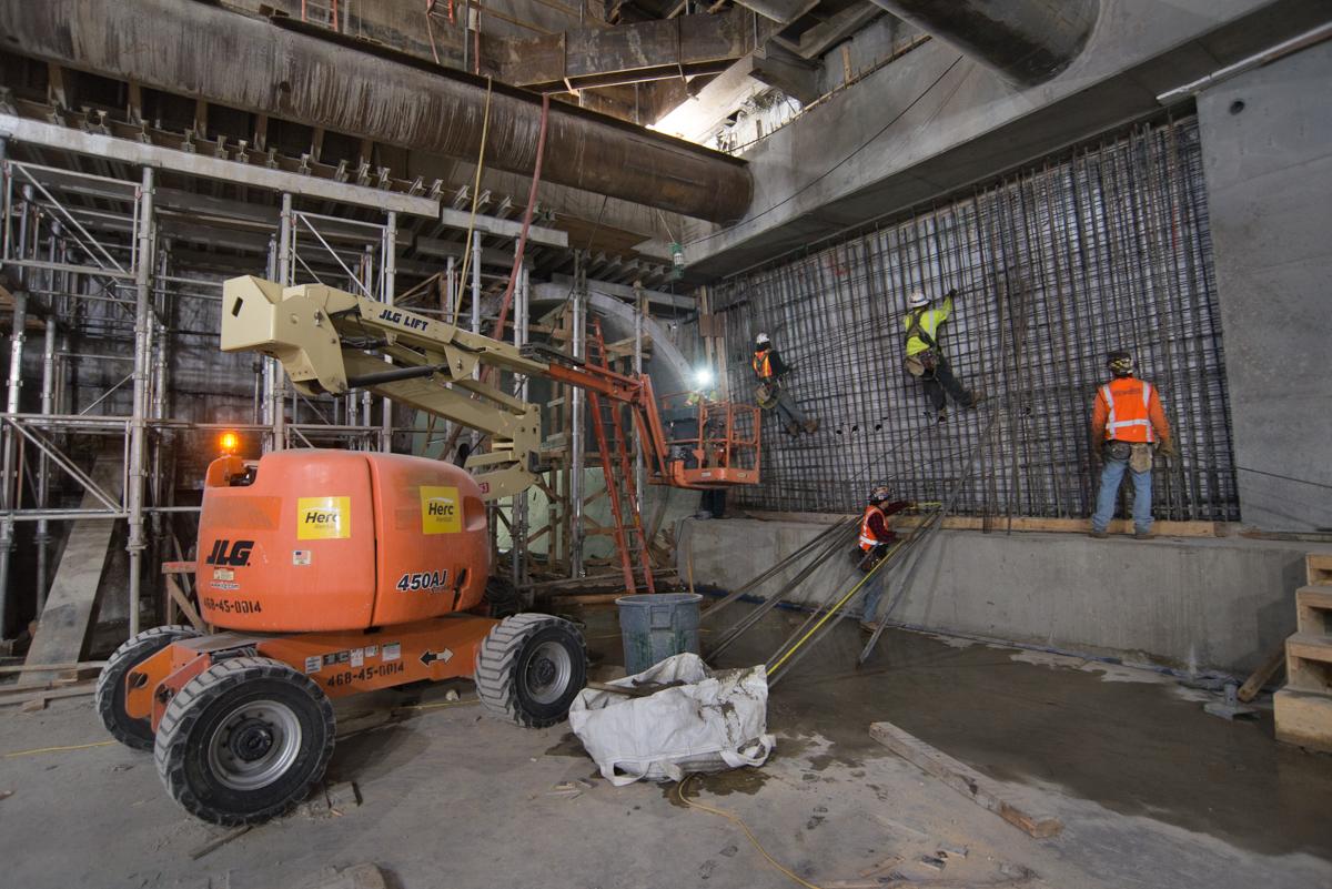 Construction crew installing rebar at Union Square/Market Street Station platform using aerial lift and equipment.