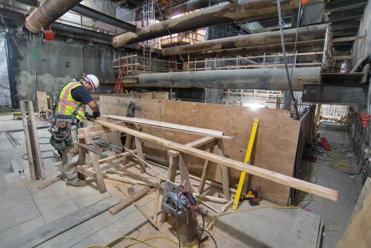 Construction worker installing wooden forms for concrete at Union Square station site.