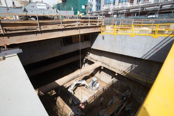 Excavation pit at Chinatown Station headhouse showing soil improvement work and construction equipment below street level.