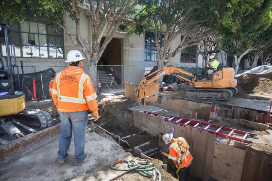 Workers in safety gear reinforcing underground utilities during Central Subway construction on 4th Street.