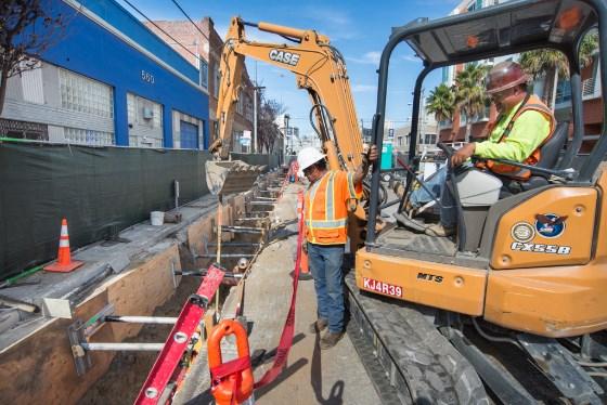 Construction crew operating excavator on 4th Street for Central Subway project installation.