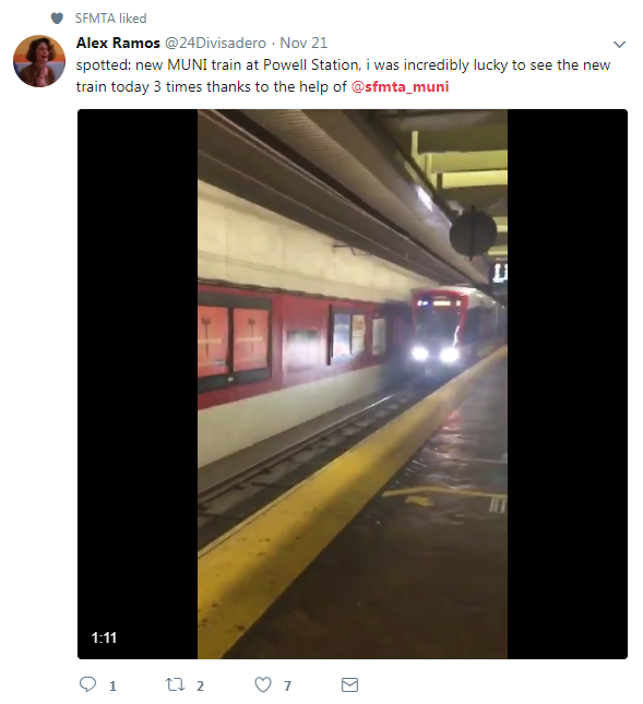 New MUNI train at Powell Station platform with illuminated headlights and red and white exterior.