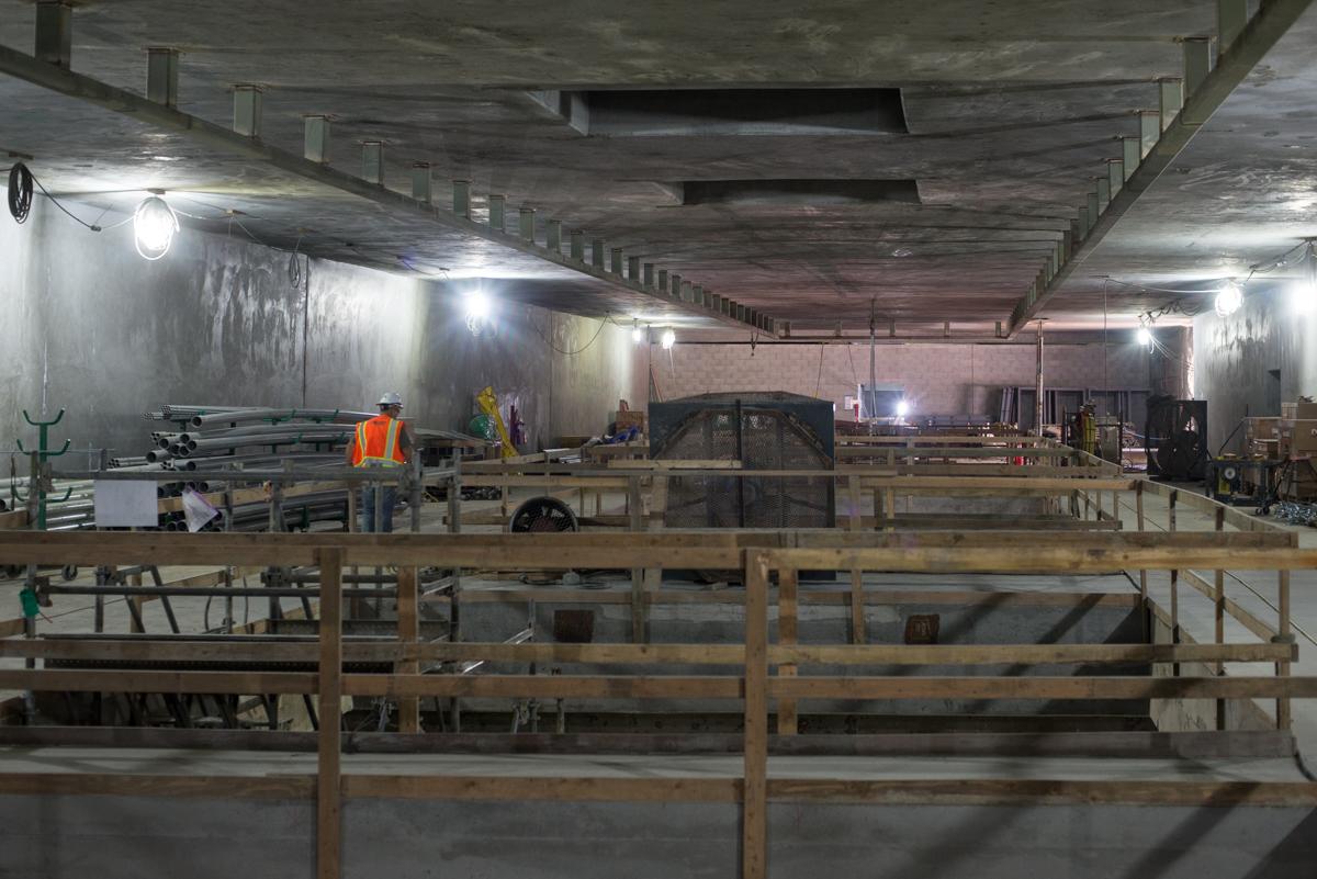 Underground transit station under construction with wooden bracing, concrete platform, and work equipment visible.