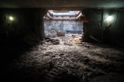 Underground station box excavation with concrete frame structure and sandy soil, lit by work lights.