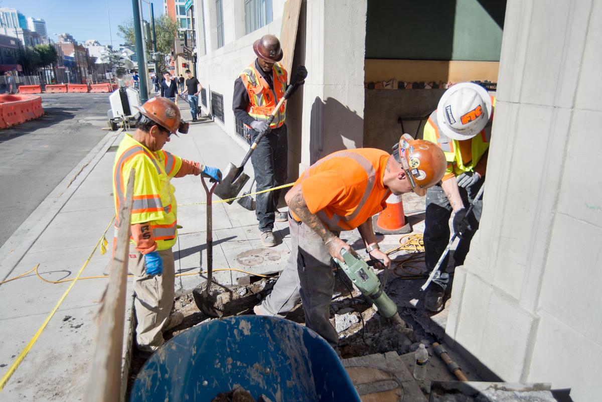 Construction workers remove and replace sidewalk section near 601 4th Street during daytime work hours.