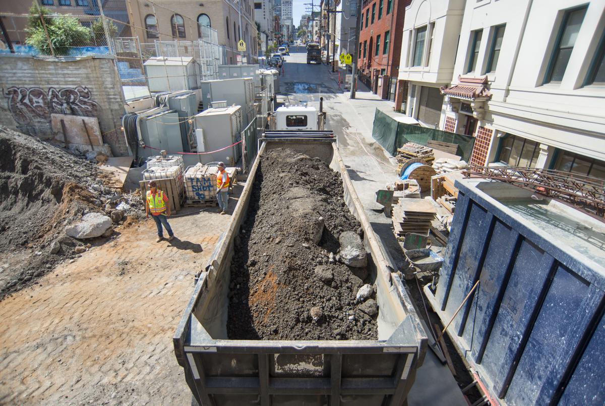 Construction excavation on Stockton Street with soil-filled truck and workers in safety vests