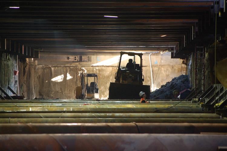 Worker operating heavy machinery inside underground tunnel excavation site during transit construction.