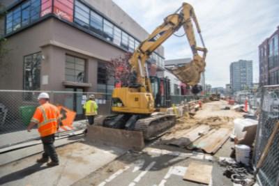 Construction excavator at 4th and Townsend Street with workers and fencing during sewer line installation.