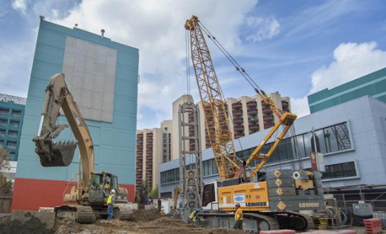 Excavator loading material into dump truck during street construction work.