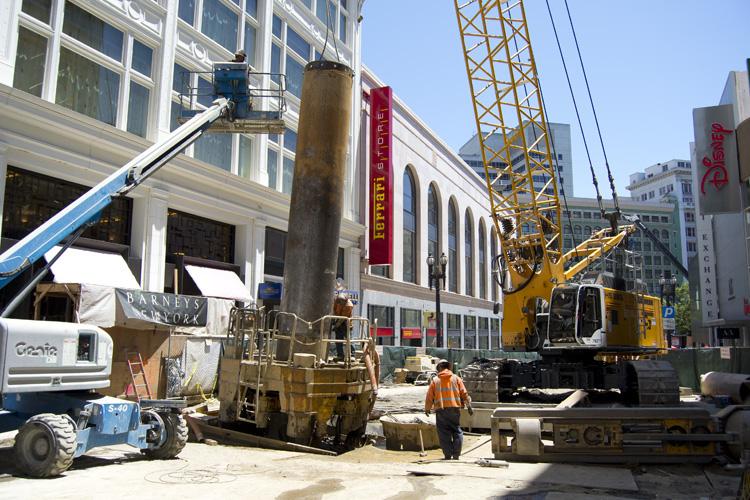 Construction equipment and workers on Stockton Street building underground walls in downtown San Francisco.