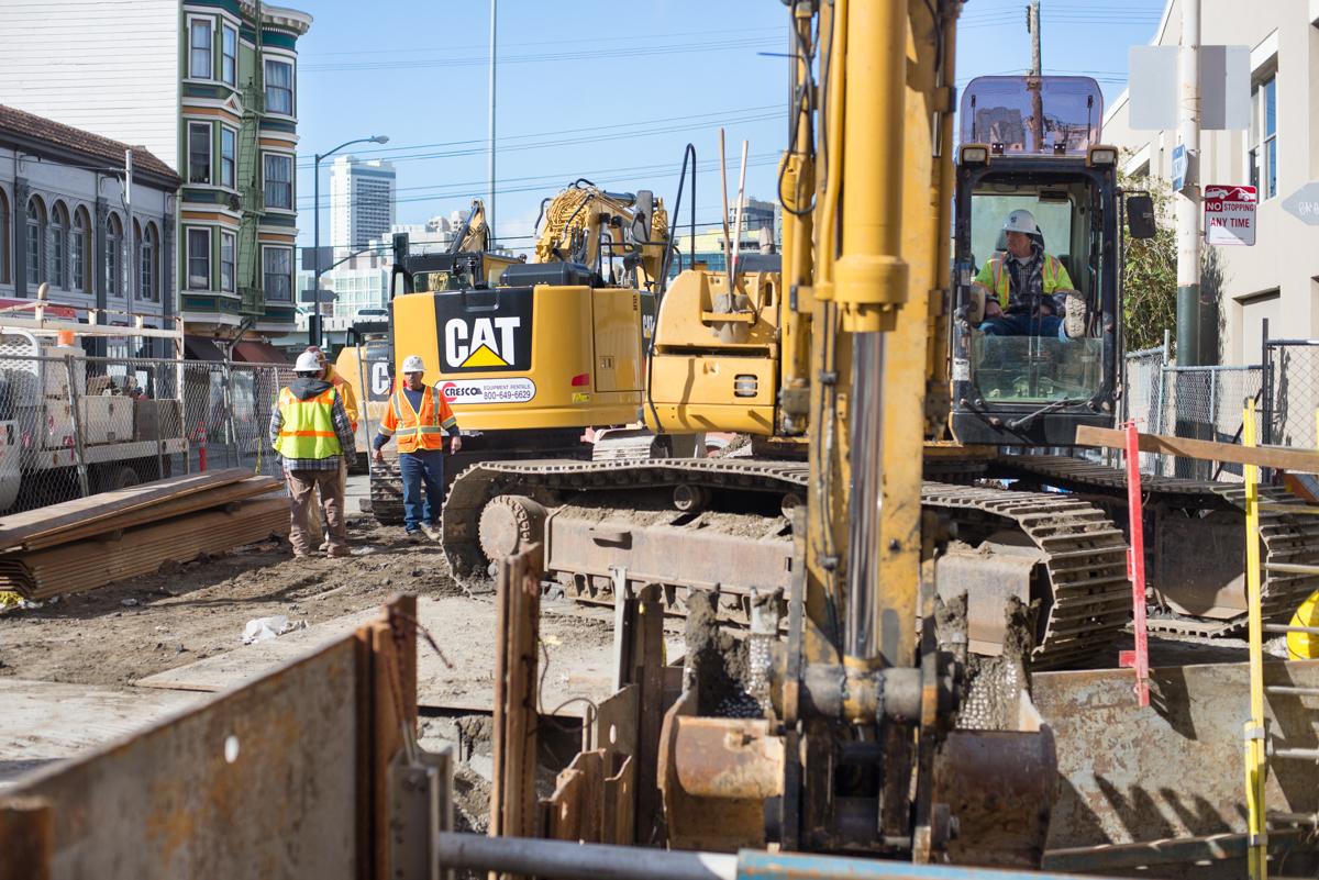 Construction crew operates CAT excavator at 4th and Welsh sewer installation site.