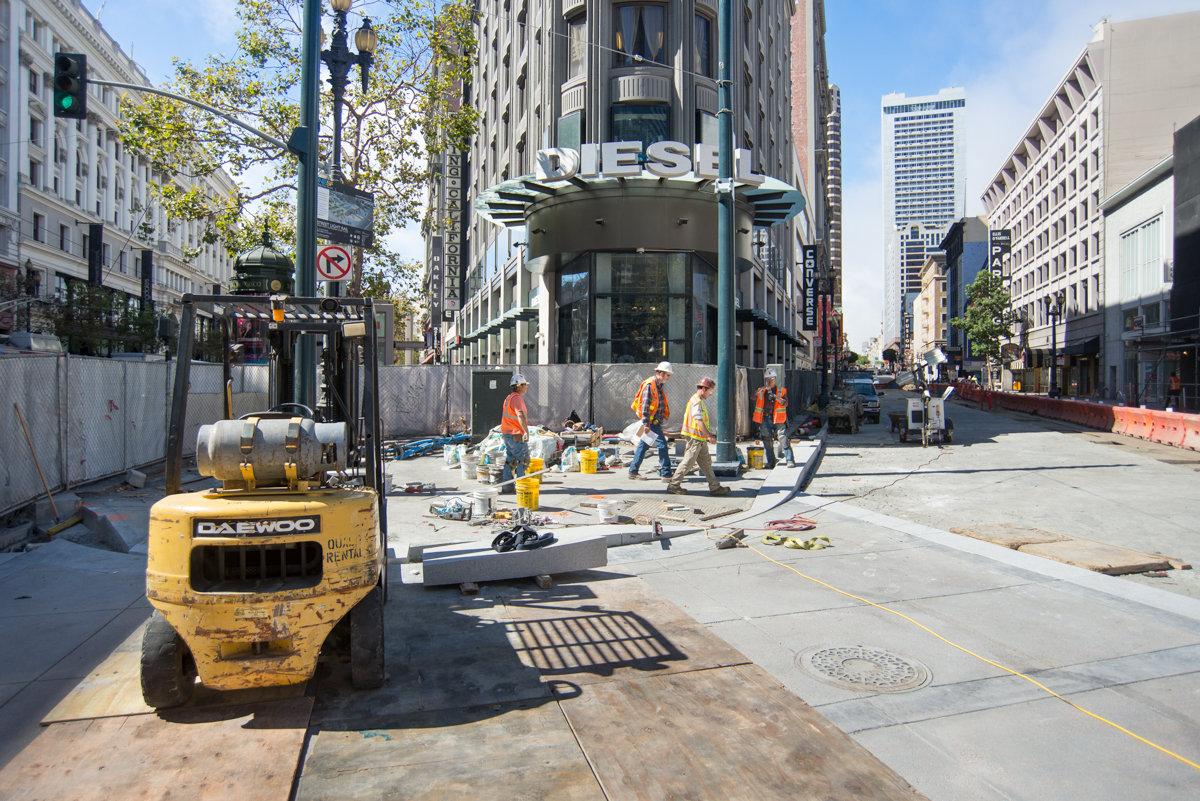 Construction workers and equipment on Stockton Street during underground transit station renovation work.