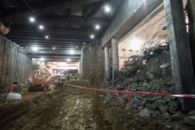 Underground construction site with exposed rock, debris, and red safety barriers at Union Square Garage.