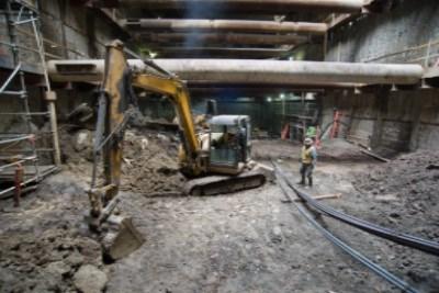 Excavator and workers performing headhouse excavation at transit construction site