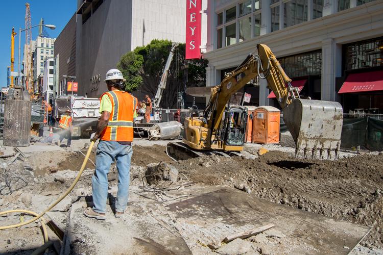Construction worker operating excavator on Stockton Street in downtown San Francisco near Union Square.