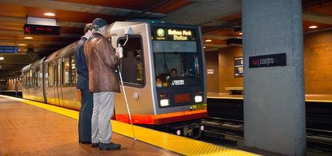 Blind passenger with cane boarding LRV at underground Muni Metro station.