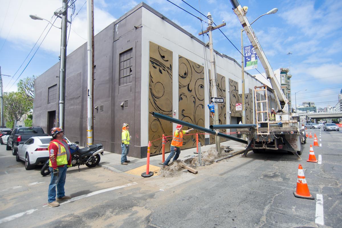 Construction crew installing overhead catenary system poles on 4th Street for Central Subway project.