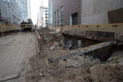Construction site at Union Square Garage showing excavation, exposed utility work, and temporary structural supports between buildings.
