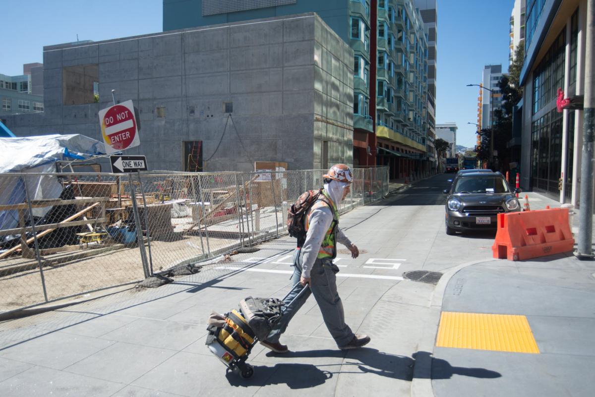 Worker rolling tool kit across Clementina Alley near Yerba Buena/Moscone Station construction site.