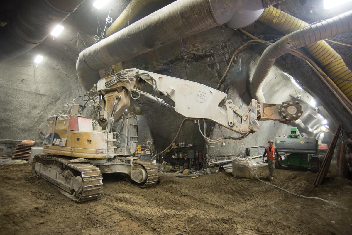 Excavator lifting materials inside underground tunnel cavern during transit construction work.
