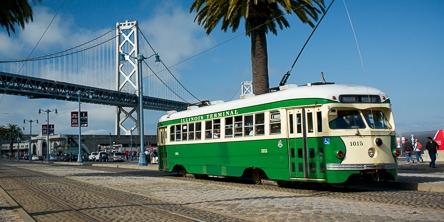 Green and cream PCC streetcar on the Embarcadero with Bay Bridge in background.