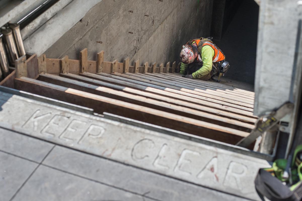 Worker installing rebar for emergency egress staircase construction beneath Stockton Street