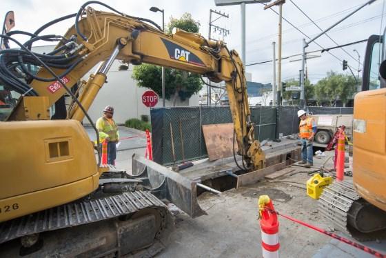 CAT excavator removes materials from trench at 4th Street Surface Station during Central Subway construction.