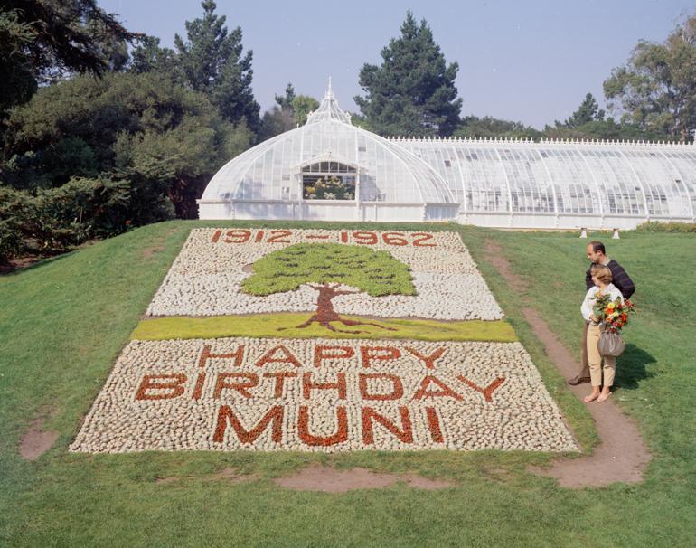 Flower bed display reading "Happy Birthday Muni" with tree design at Golden Gate Park Conservatory of Flowers