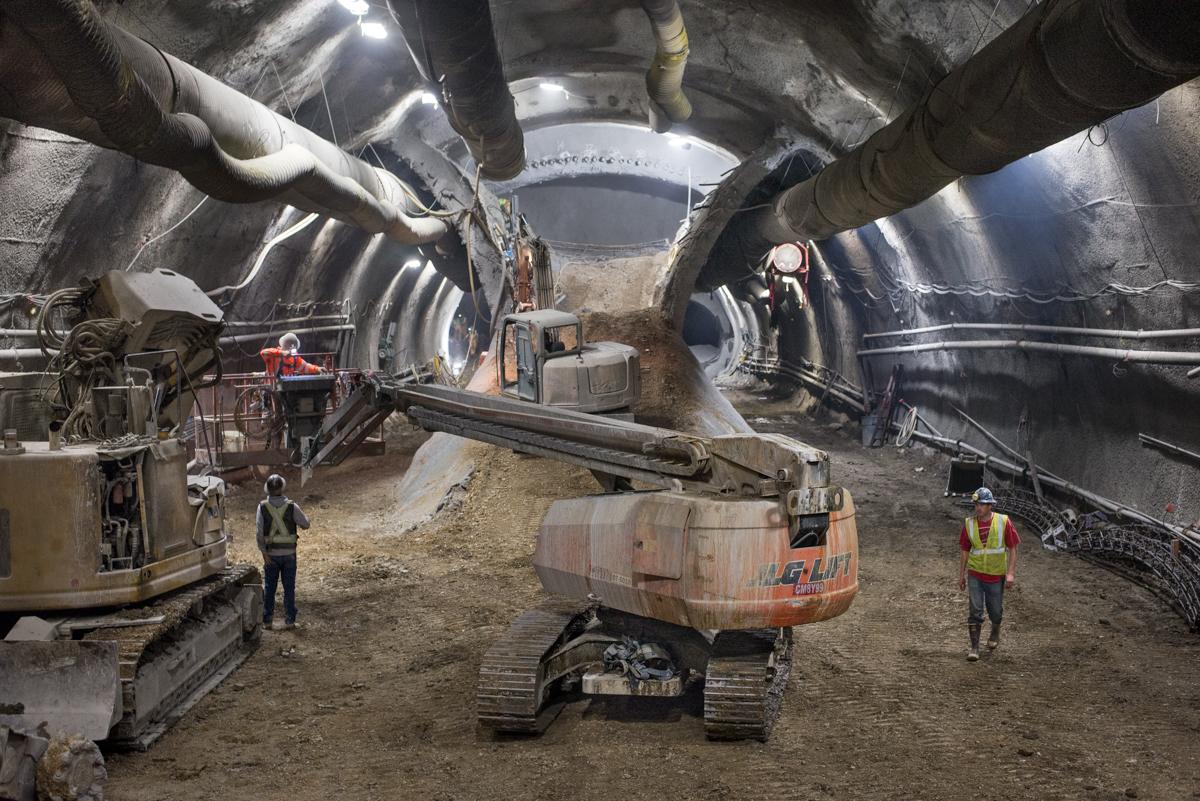 Workers and equipment excavate underground tunnel for Central Subway station construction in San Francisco.