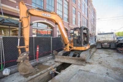 Yellow excavator at construction site on 4th Street and Townsend Street for sewer line installation.