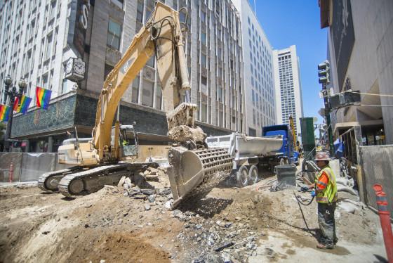 Excavator loads debris into dump truck during Central Subway construction in downtown San Francisco.