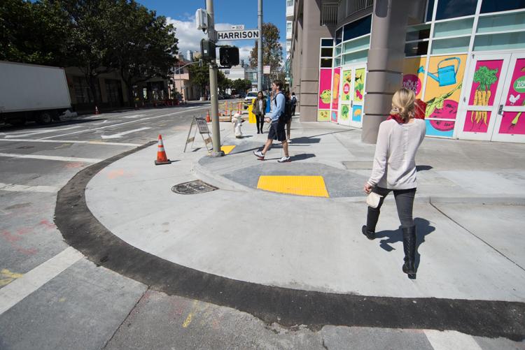 Person on scooter on 4th Street with construction work, yellow ramps, and colorful storefront visible.
