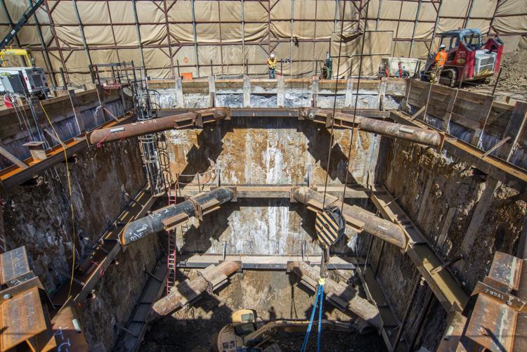 Tunnel boring machine retrieval shaft with temporary cross-braces and reinforced concrete walls under construction.