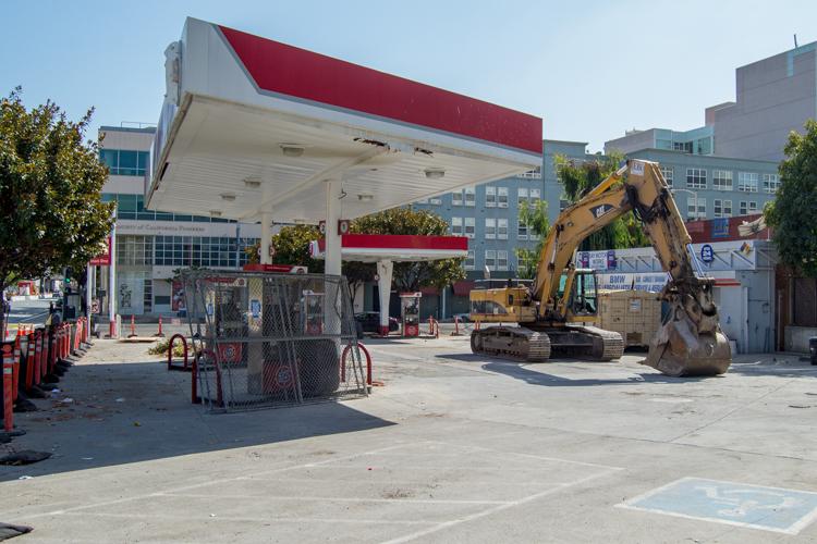 Demolished gas station at 4th and Folsom with excavator and construction barriers, urban buildings in background.