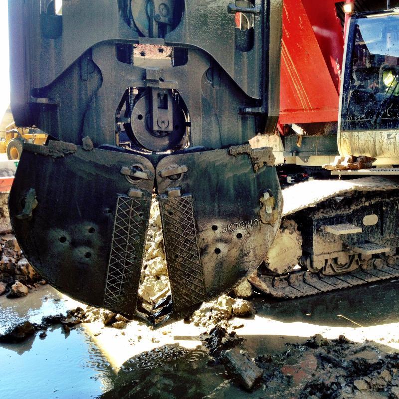 Mechanical grab bucket removing excavated material at tunnel construction site.