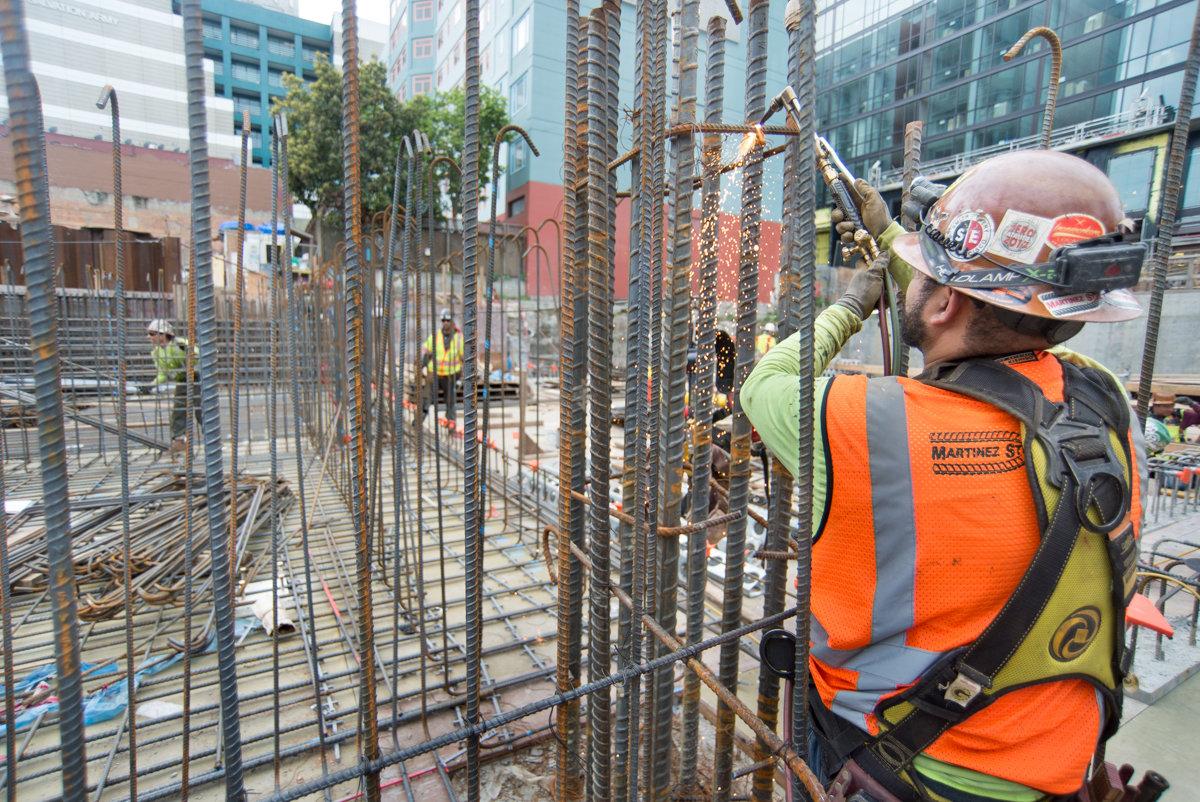 Worker in safety gear cutting rebar at Central Subway construction site in San Francisco.