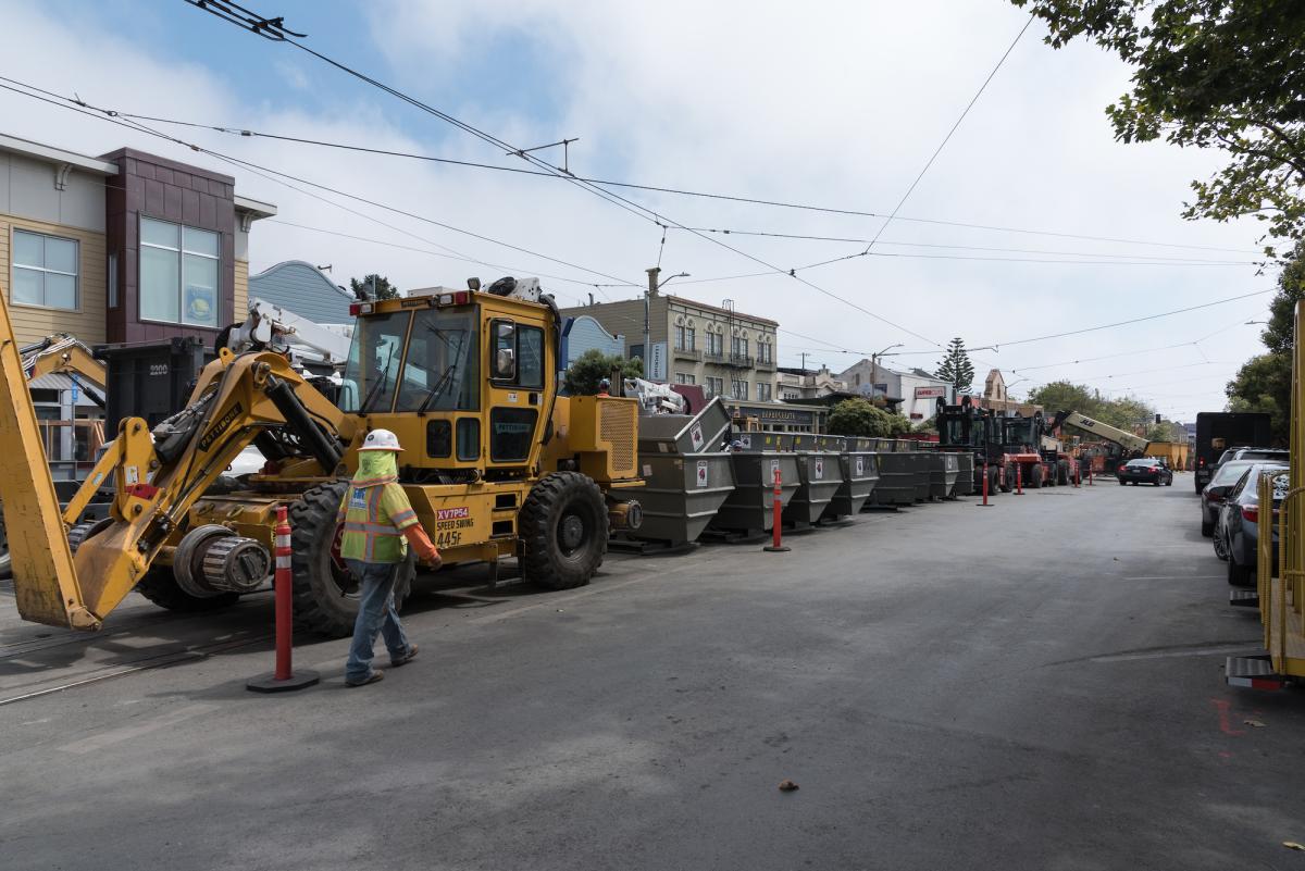 Work train loaded with construction equipment and machinery on West Portal Avenue street.