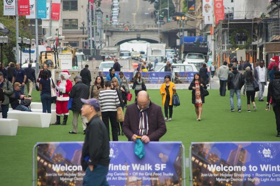 Crowds of people gather on a green plaza on Stockton Street in Union Square during Winter Walk SF event.