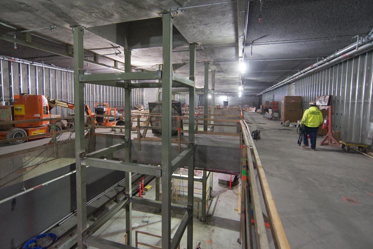 Interior construction site with steel framework, equipment, and workers in safety gear at transit station.