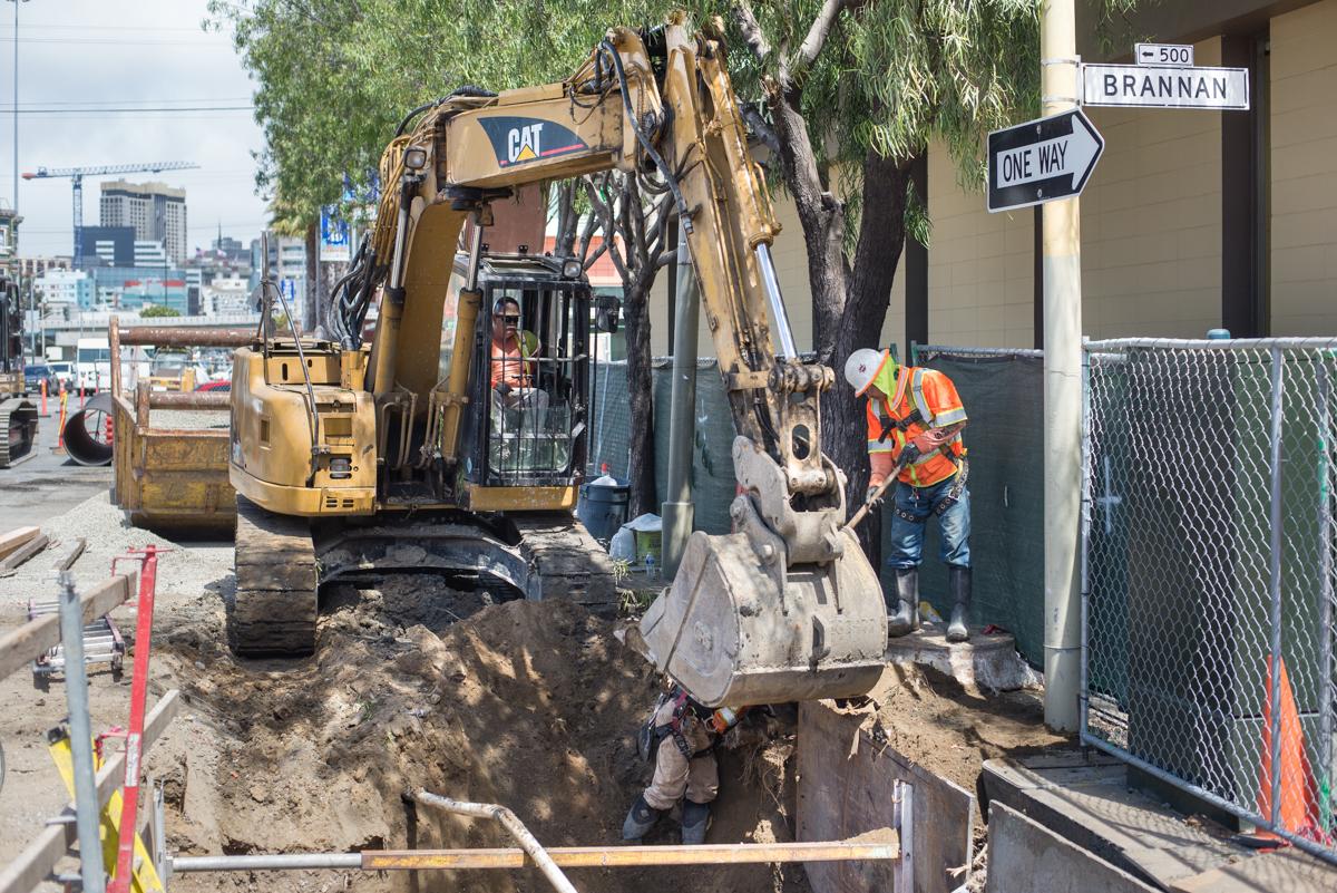 CAT excavator digs at 4th and Brannan Street for water line installation work.