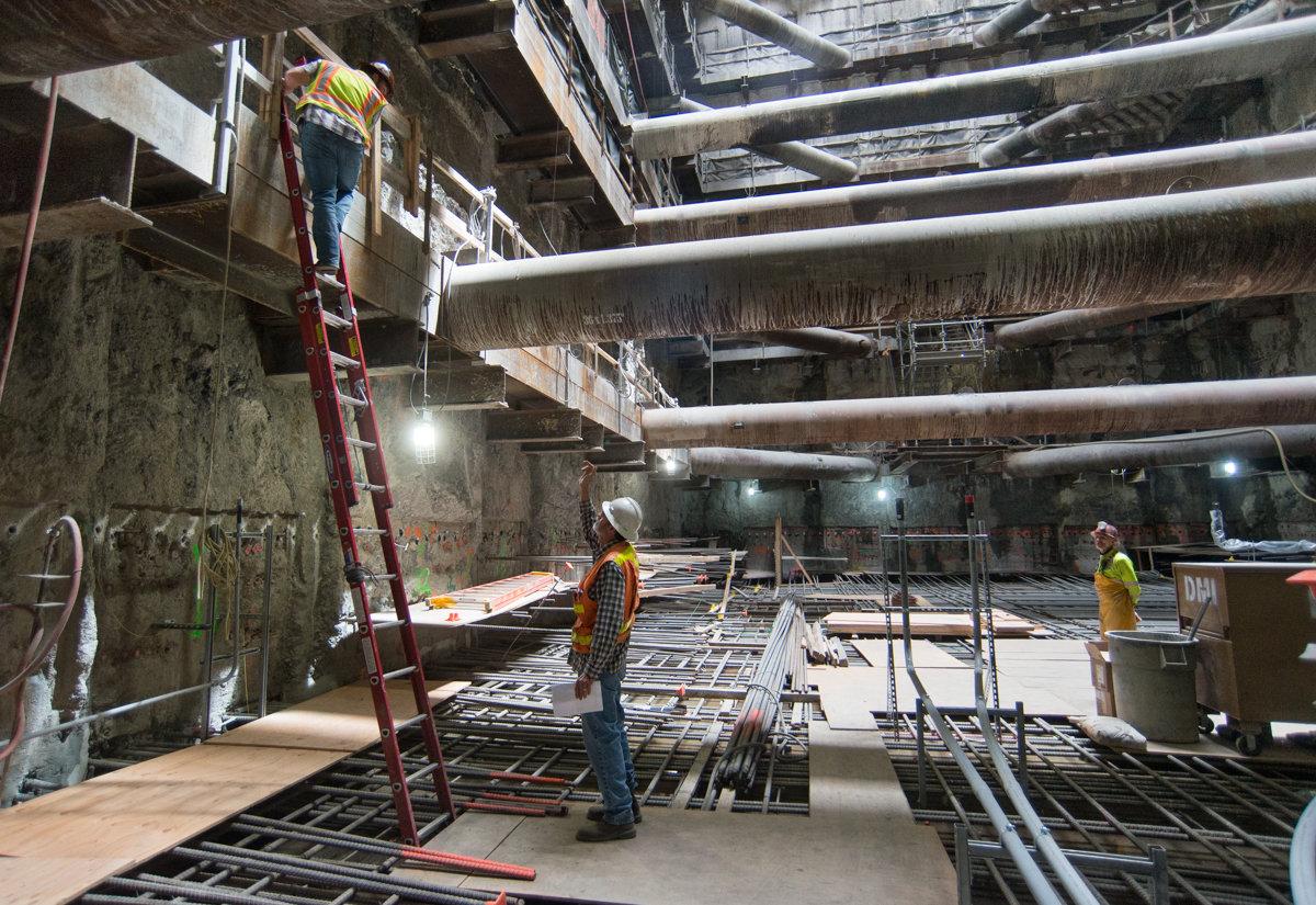 Construction workers on scaffolding inside Chinatown Station headhouse during transit project development.