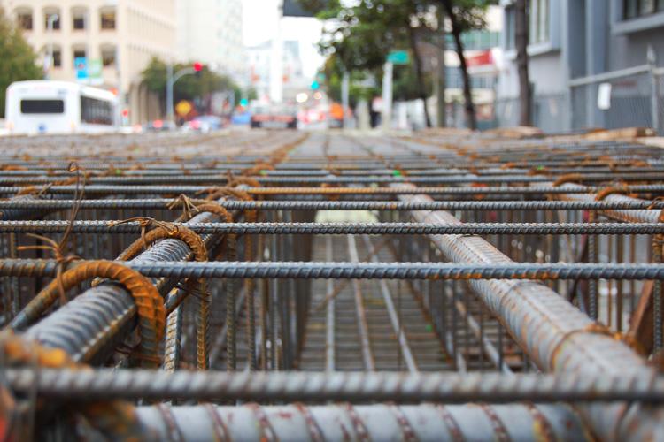 Rebar cage with wire ties installed on 4th Street construction site, city street visible in background.