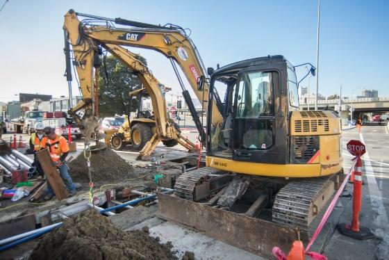 CAT excavator and workers performing utility work at 4th Street and Bryant Street construction site.