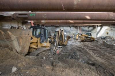 Construction equipment and machinery stored in excavation trench during transit tunnel construction.