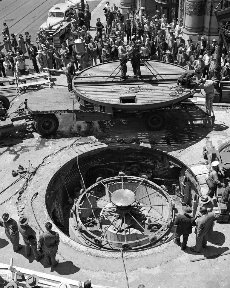 Workers install cable car turntable at Powell and Market Streets, 1950, with crowd observing construction.
