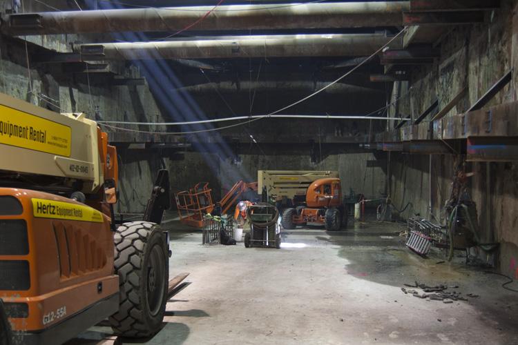 Interior of underground tunnel with orange heavy equipment and machinery during Central Subway construction.