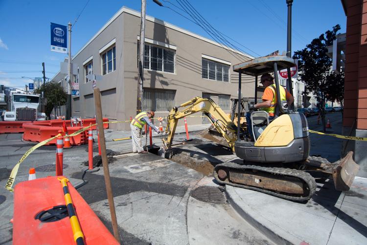 Construction crew operates small excavator on 4th Street near Bryant during Central Subway utility work.
